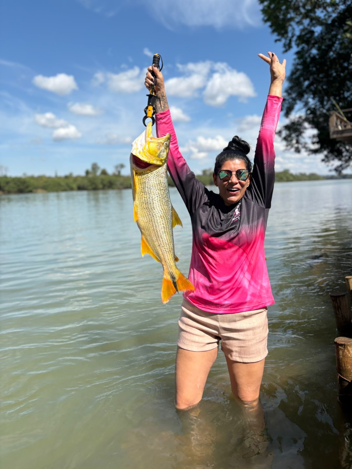 Pescadora comemorando com o peixe nas mãos no rio